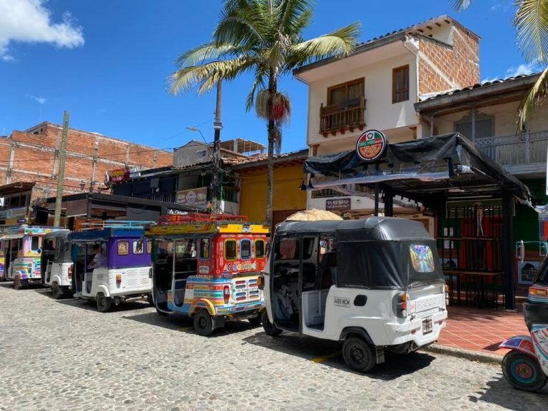 Local tuk-tuks in Guatape town center on a sunny day Colorful tuk-tuks parked along a cobblestone street in the center of Guatape, Colombia